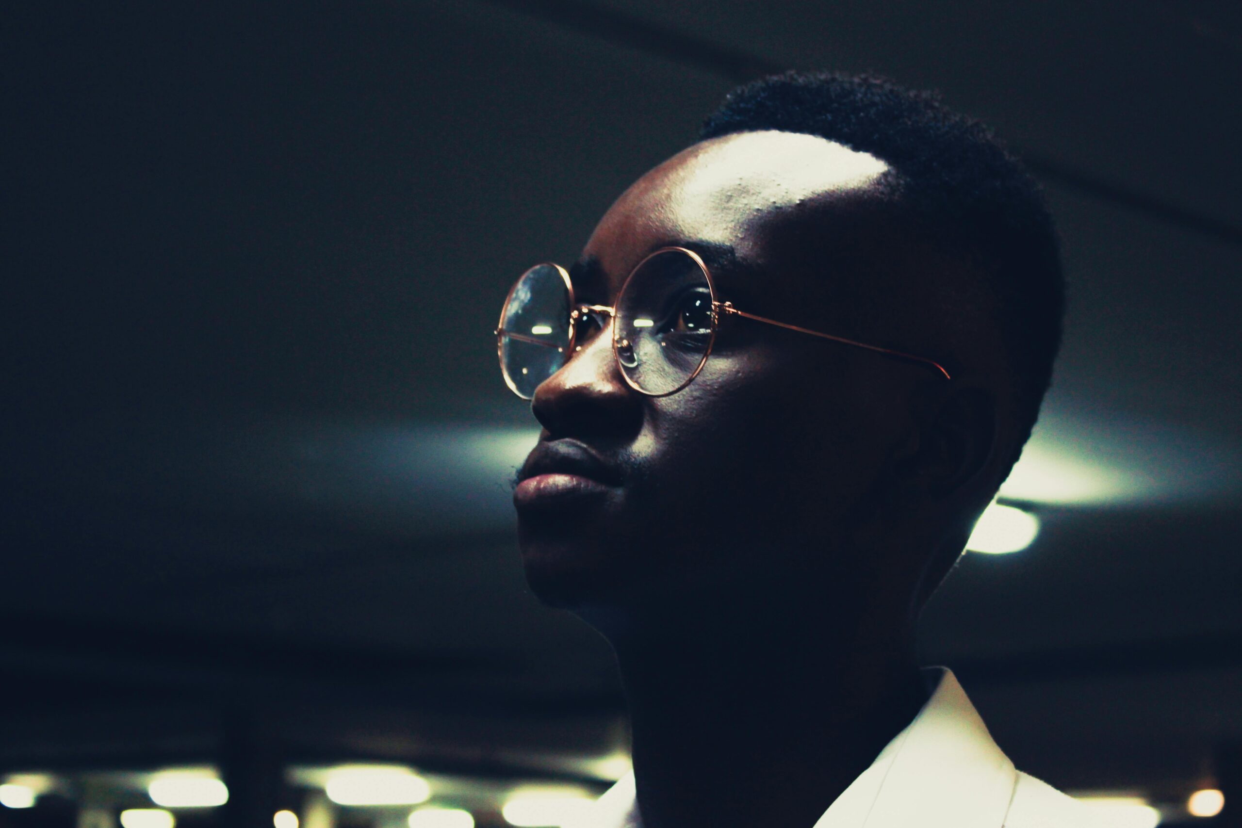 Stylish portrait of a man wearing eyeglasses under moody lighting.